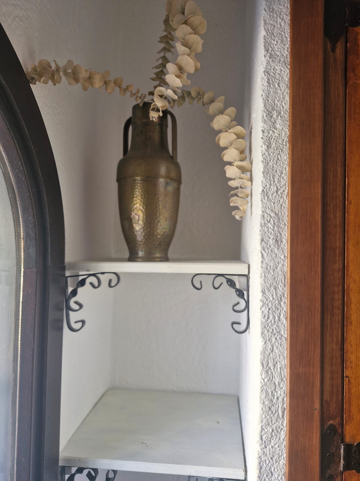 Brass vase with eucalyptus in wall niche